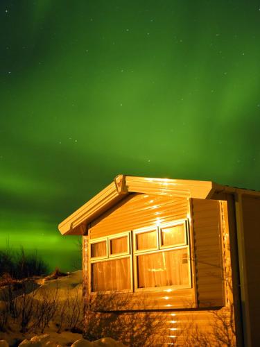 a cabin under the greenorthern lights in the sky at Lækjarkot Rooms and Cottages with Kitchen in Borgarnes