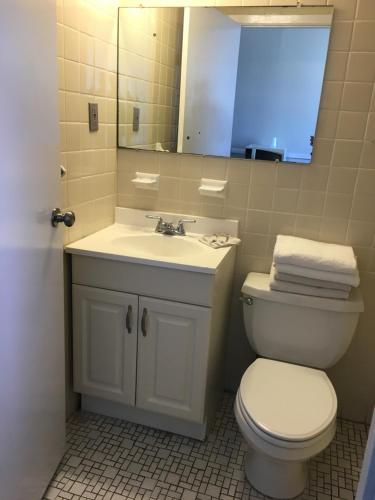 a bathroom with a toilet and a sink and a mirror at Four Winds Motel in Seaside Heights