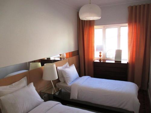 リスボンにあるPríncipe Real Sunnyのベッド2台と窓が備わるホテルルームです。