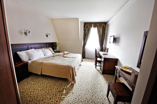 a bedroom with a bed and a desk and a window at Hotel Chutor Kozacki in Łukowe