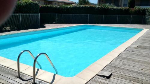 une grande piscine bleue avec une terrasse en bois dans l'établissement Chambre avec petit déjeuner, à Carcassonne