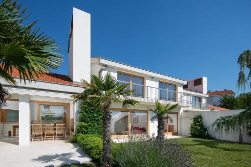 a white house with palm trees in front of it at Casa Vidmar in Klimno