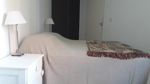 Un dormitorio con una cama con una manta. en Espacio C Ambrosio Olmos en Córdoba