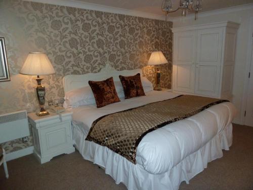 a bedroom with a large white bed with two lamps at The Belmore in Sale