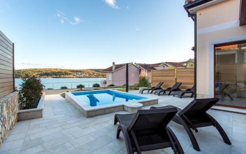 a patio with a swimming pool and chairs and a house at Villa Ema in Čižići
