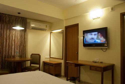 a hotel room with a bed and a television on the wall at Comfort Hotels in Coimbatore