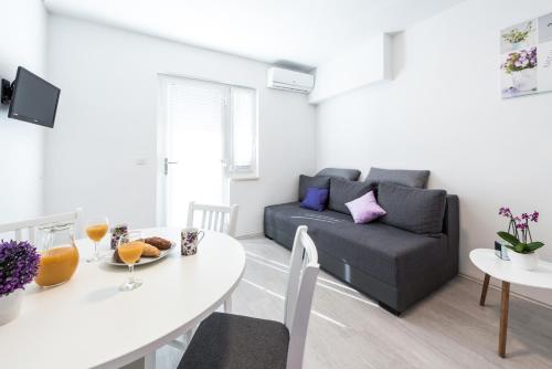 un soggiorno con tavolo bianco e divano di Apartments Nika a Cavtat