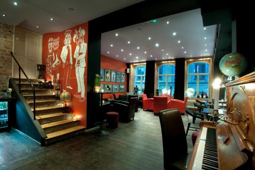 a lobby with a staircase and a bar with red chairs at Hotel Hellsten in Stockholm