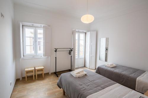 a room with two beds and a table and two windows at 1977 in Faro