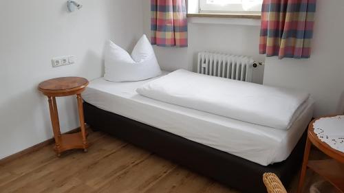 ガルミッシュ・パルテンキルヒェンにあるAm Fraßl's Bicheのテーブル付きの客室の小さなベッド1台分です。