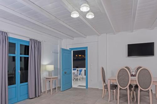 une salle à manger avec des portes bleues, une table et des chaises dans l'établissement Aegean Sea Villas, à Livadi Astypalaias