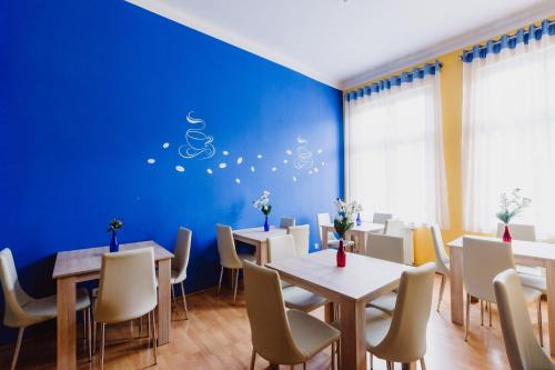 een eetkamer met tafels en stoelen en een blauwe muur bij Hostel Tara in Krakau