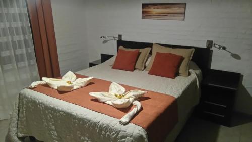 - une chambre avec un lit orné de 2 fleurs blanches dans l'établissement Casa de descanso Costa Azul, à La Floresta