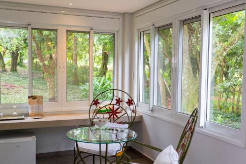 a kitchen with windows and a glass table and chairs at Hotel Pousada do Bosque in Ponta Porã
