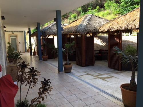 a resort with a patio with plants and umbrellas at Residence Hôteliere Hurlevent in Grande Anse