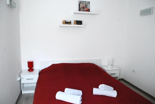 1 Schlafzimmer mit einem roten Bett und 2 Handtüchern in der Unterkunft Modern City Apartments in Sarajevo