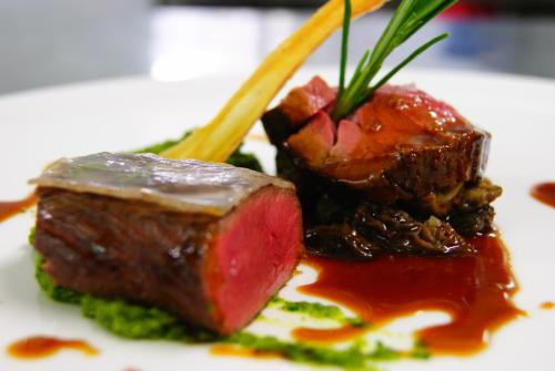 a piece of meat with sauce on a plate with chopsticks at Hotel Seefischer - Finest Hideaway in Döbriach