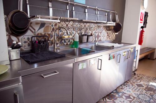 a stainless steel kitchen with a sink and cabinets at The Lights Hostel in Málaga