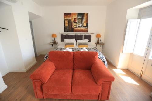 a red couch in a room with a bed at Casa Rural Miller's of Frigiliana in Frigiliana