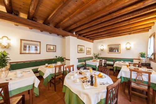 Un comedor con mesas y sillas y techos de madera. en Ca' Tessera Venice Airport, en Tessera