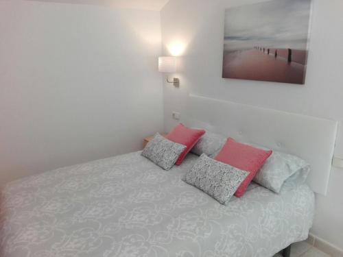 Schlafzimmer mit einem Bett mit rosa und grauen Kissen in der Unterkunft Cozy Loft Torremolinos in Torremolinos