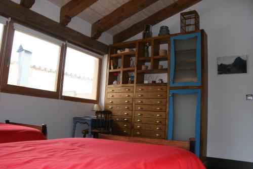 1 dormitorio con cama roja y armario de madera en Casa Rural Velliza, en Velliza