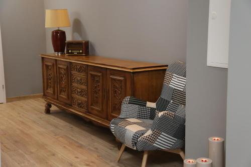 a chair next to a wooden cabinet with a lamp at Pod Beczką in Augustów
