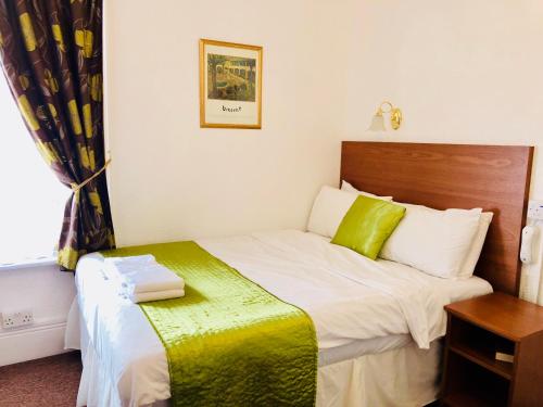 a bedroom with a bed with a green and white blanket at Ilfracombe House Hotel - near Cliffs Pavilion in Southend-on-Sea