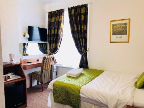 A bed or beds in a room at Ilfracombe House Hotel - near Cliffs Pavilion