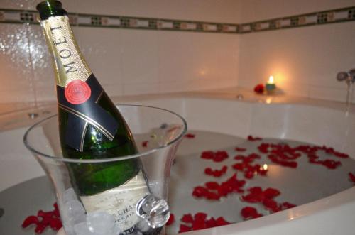 a bottle of champagne in a glass next to a bath tub at Le Saint-Etienne in Trujillo