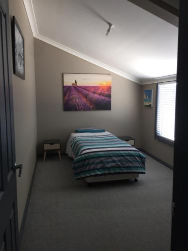 una camera da letto con un letto e un quadro sul muro di Cottage in the Country a Tumut
