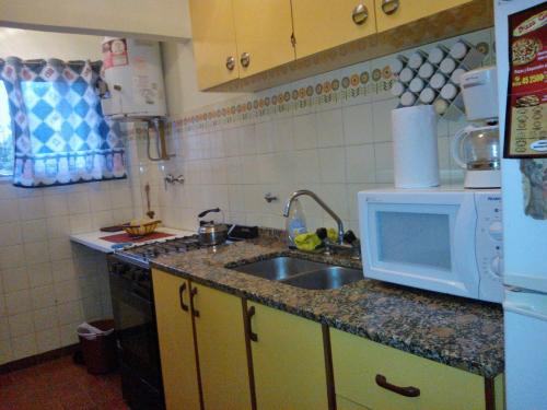 a kitchen with a sink and a microwave at Edificio Familiar Mar Veo in Villa Gesell