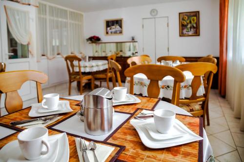 a dining room with a table with plates and silverware at Kata Panzió in Szeged