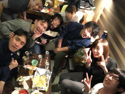 a group of people sitting around a table making peace signs at Shabby House in Sapporo