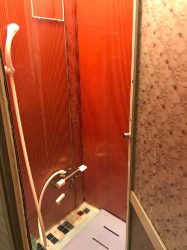 a shower in a bathroom with a red wall at Shabby House in Sapporo