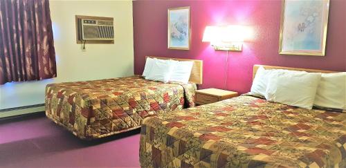 a hotel room with two beds and purple walls at AmeriVu Inn & Suites-Avon in Avon