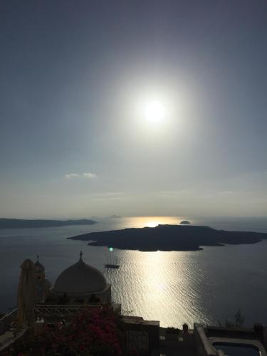 a sun setting over a large body of water at Le Petit Greek in Fira