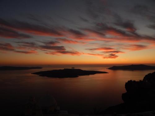 a sunset over a large body of water at Le Petit Greek in Fira