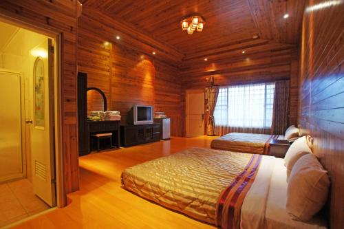 a bedroom with two beds and a television in a room at Bao Kang Flower Farm in Nanzhuang