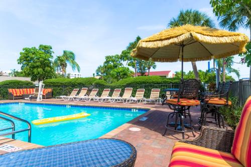 uma piscina com cadeiras, uma mesa e um guarda-sol em Tropical Beach Resorts - Sarasota em Sarasota