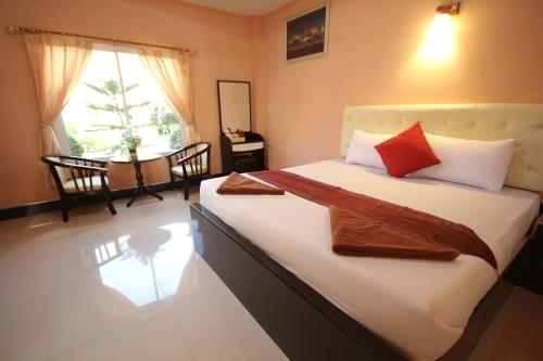 a bedroom with a bed with white sheets and red pillows at Windsor Resort in Lop Buri