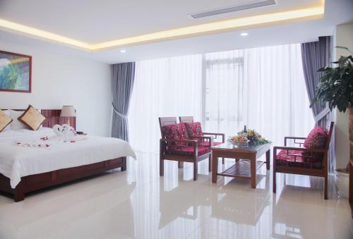 a bedroom with a bed and chairs and a table at Vinh Hoang Hotel in Dong Hoi