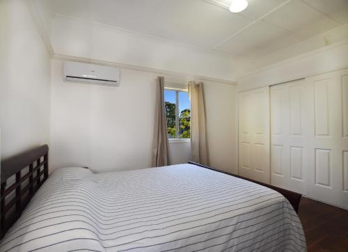 a white bedroom with a bed and a window at Absolute Waterfront in Brisbane