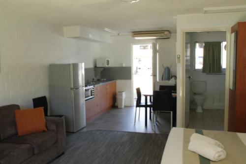 ein Wohnzimmer und eine Küche mit einem Sofa und einem Tisch in der Unterkunft Whitehaven Beachfront Holiday Units in Airlie Beach