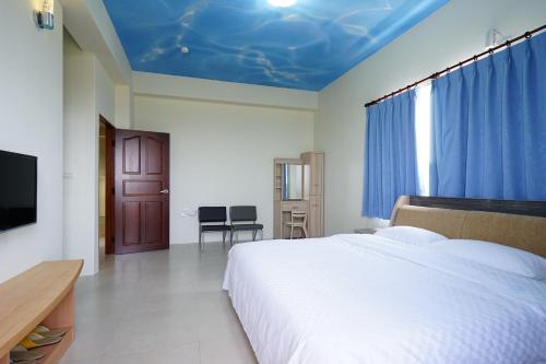 a bedroom with a large bed with a blue ceiling at Penghu Sun House in Magong
