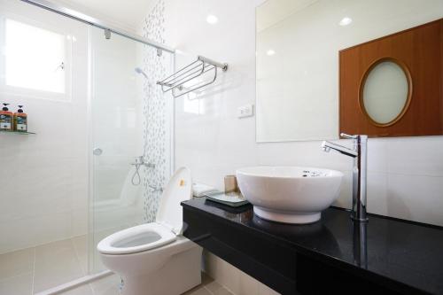 a white bathroom with a sink and a toilet at Penghu Sun House in Magong