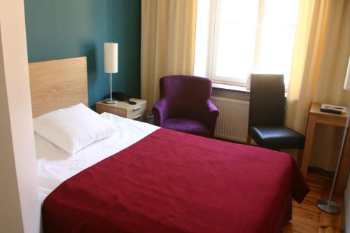 a bedroom with a bed and a purple chair at Rex Hotel in Stockholm