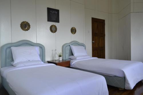 two beds in a room with white sheets at Mesilau Mountain Retreats in Kundasang