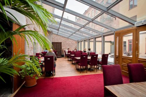 un salón acristalado con mesas y sillas y personas sentadas en una mesa en Rex Hotel, en Estocolmo