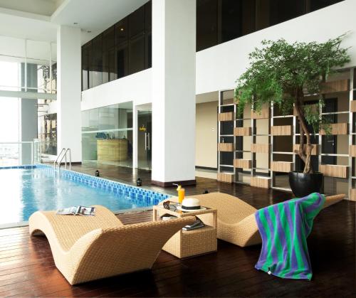 a hotel lobby with a pool and two chairs and a table at ASTON Bellevue Radio Dalam in Jakarta